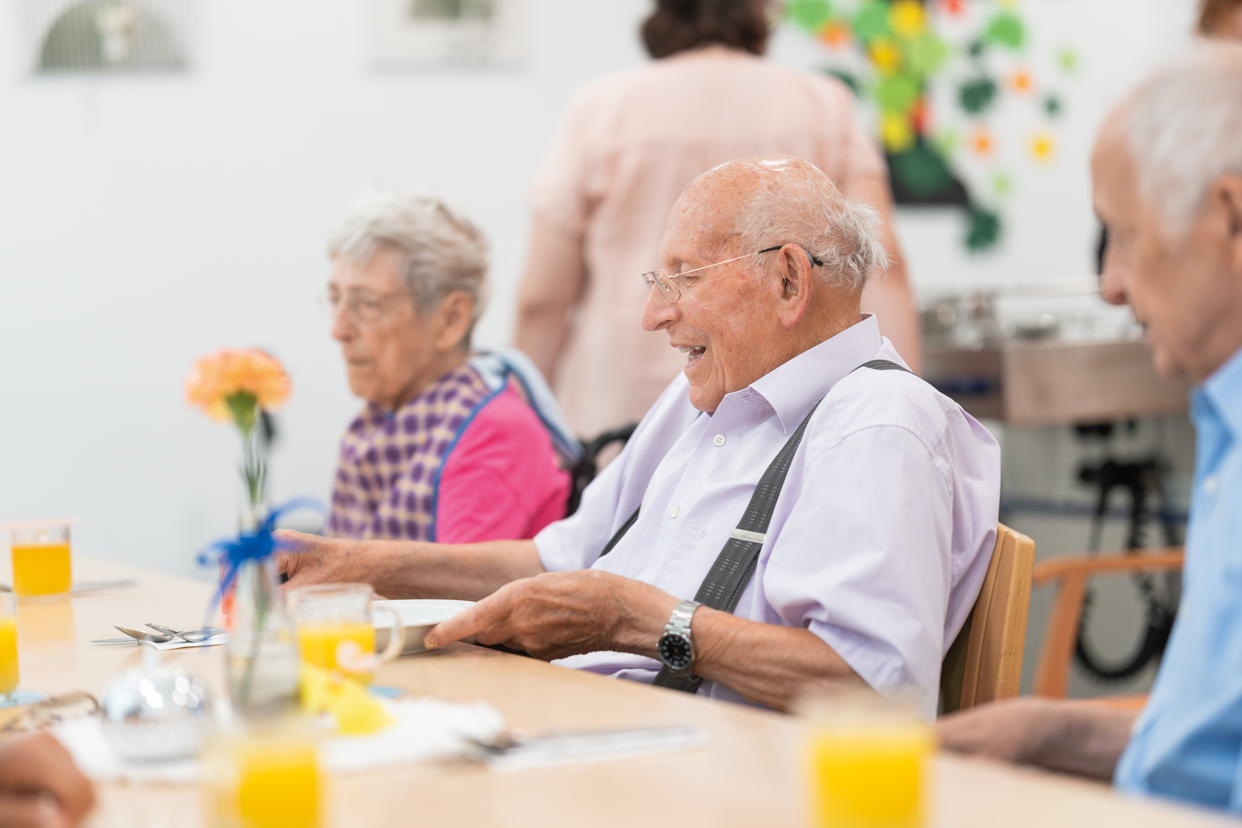 Gemeinsames Essen in Gesellschaft Älterer Herr sitzt gemeinsam mit anderen Menschen an einem Esstisch