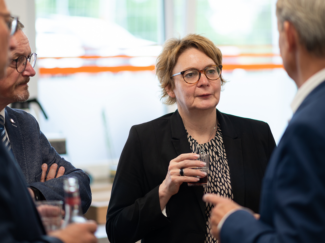 Vier Personen, in der Mitte Ministerin Daniela Behrens im Gespräch mit Vorstand Michael Dieckmann