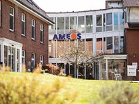 Der Eingang des AMEOS Klinikums Middelburg mit einer grünen Wiese im Vordergrund und dem AMEOS Logo über dem Eingang.
