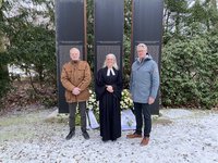 Drei Personen vor dem Mahnmal des AMEOS Klinikums Neustadt.